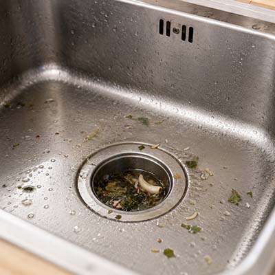 Verstopfter Abfluss in einer Küchenspüle mit stehendem Wasser und Speiseresten